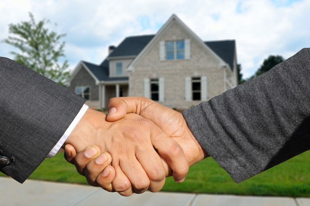 Handshake between two individuals with a house in the background, symbolizing the partnership in the home buying process in Middle Tennessee.