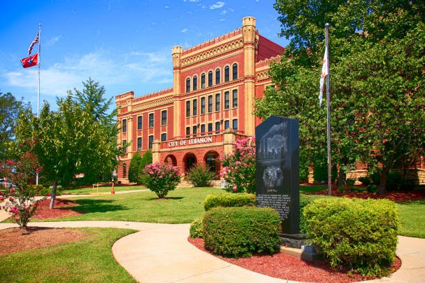 Historic City Hall of Lebanon, Tennessee, featuring vibrant landscaping, commemorative monument, and flags, representing the community's charm and rich history.