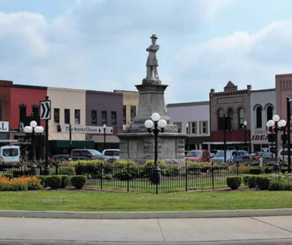 Town square in Lebanon, Tennessee featuring a central monument surrounded by landscaped gardens, historical buildings, and street lamps, representing the community's charm and local character.