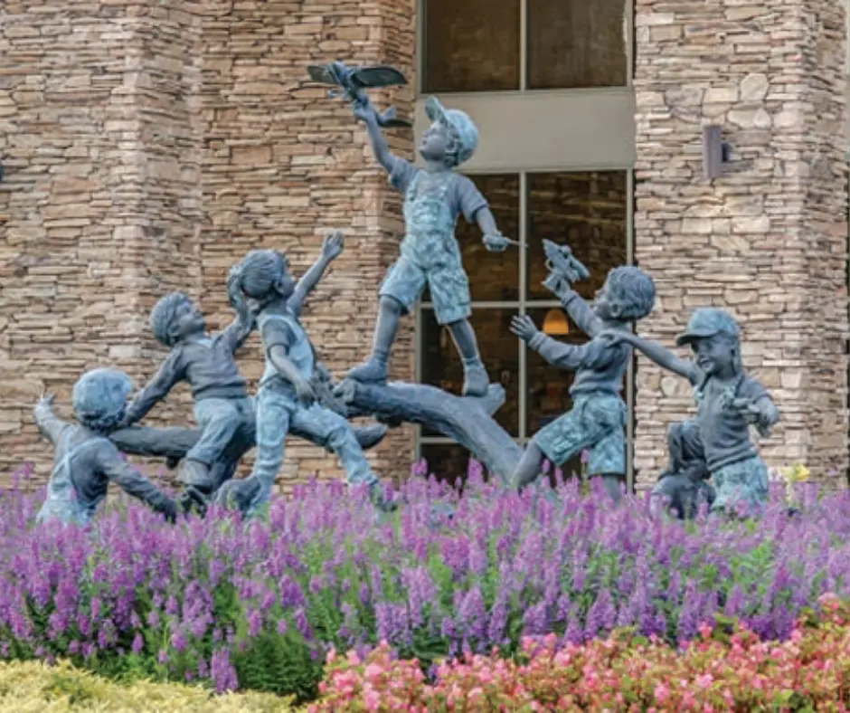 Bronze sculpture of children playing joyfully in a vibrant garden, symbolizing community and connection in Davidson County, Nashville.