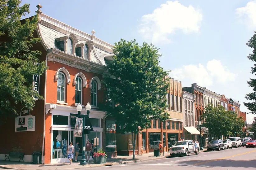 Historic storefronts and shops in Nolensville, Tennessee, showcasing small-town charm and community atmosphere, with trees lining the street and clear blue skies.