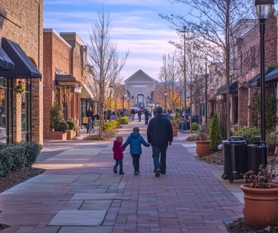 Family walking hand-in-hand along a charming shopping street in Mt. Juliet, TN, showcasing local businesses and a welcoming community atmosphere.