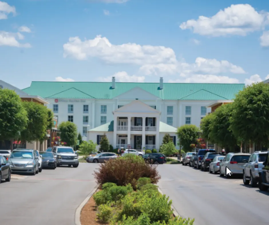 Modern hotel with green roof and welcoming entrance, surrounded by trees and parked cars, located in a vibrant community in Williamson County, Tennessee.