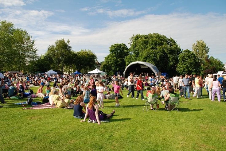 Crowd enjoying a concert in Thompson’s Station Park, with families on the grass, tents in the background, and a stage set up for live music.